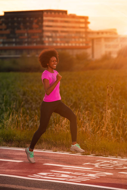 a young African American woman jogging outdoors - Фото, зображення