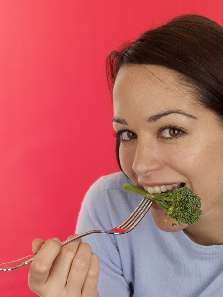 Mujer joven comiendo brócoli de tallo blando
 - Foto, Imagen