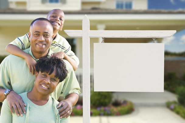 Familia afroamericana frente a un cartel inmobiliario en blanco y una casa
 - Foto, imagen