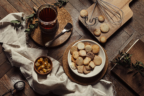 Hot tea in antique cup holder with sugar cookies on old brown wooden background. - Valokuva, kuva
