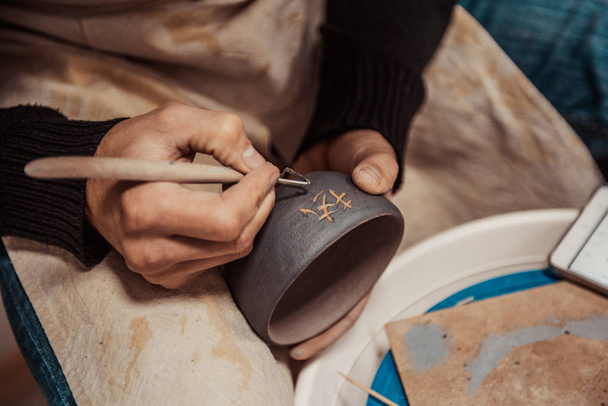 Γκρο πλαν, στα χέρια του καλλιτέχνη για να διαμορφώσετε ένα πήλινο Κύπελλο γράφοντας τον κινεζικό χαρακτήρα - Φωτογραφία, εικόνα