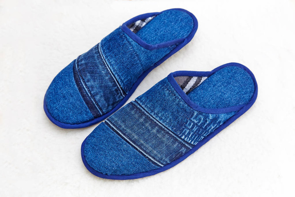 Zapatillas de mezclilla azul sobre una alfombra de lana de oveja blanca
 - Foto, imagen