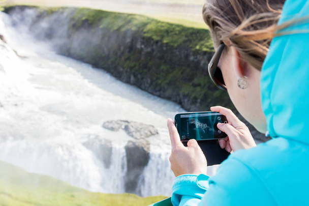 Woman photographing a waterfall with a mobile phone - Φωτογραφία, εικόνα