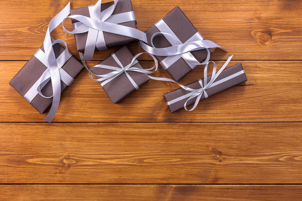 Подарки в подарочных коробках на деревянном фоне с копировальным местом
 - Фото, изображение