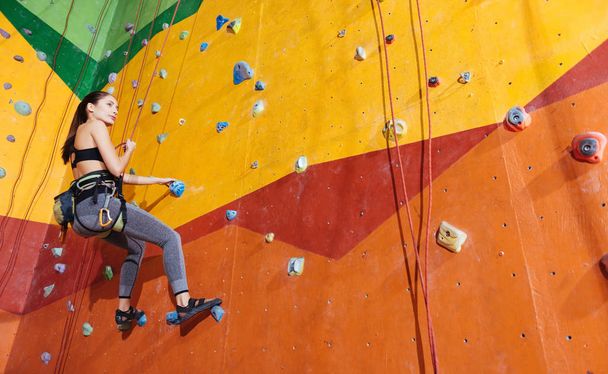 Active woman climbing up the wall in gym - Foto, Imagem