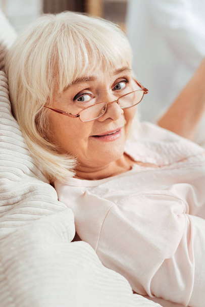 Pleasant delighted aged woman lying in bed - Photo, Image