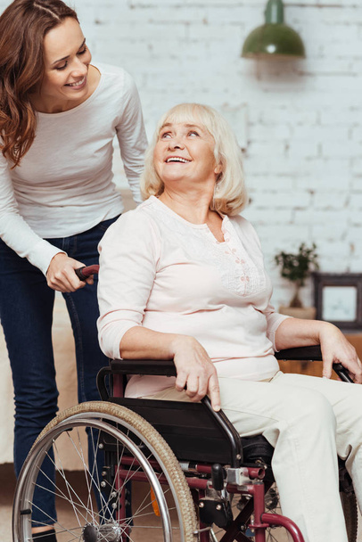Pleasant woman taking care of her grandmother in wheelchair - Фото, зображення