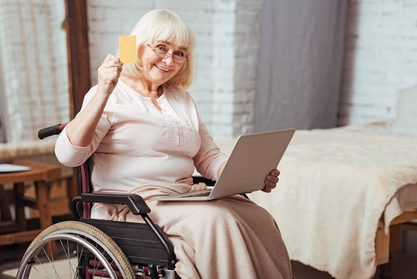 Positive elderly woman using laptop - Fotó, kép