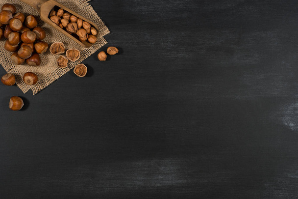 Hazelnuts in a wooden scoop on a black chalkboard. - Photo, image