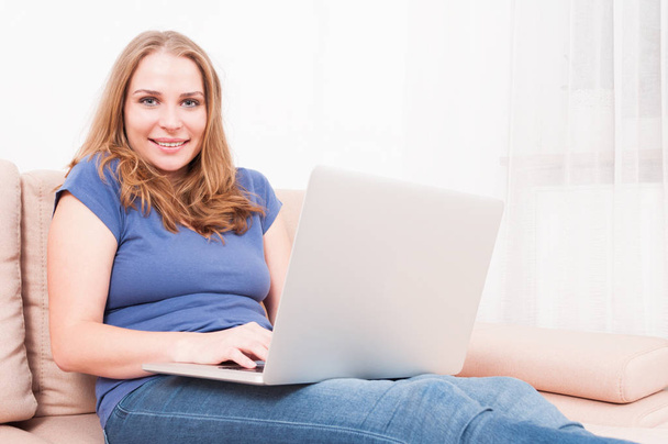 Kobieta siedzi na kanapie z laptopem i wpisując - Zdjęcie, obraz