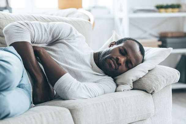 Man lying on sofa and touching stomach - Photo, image
