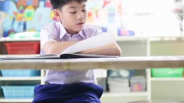 Asiatico bambino in studente uniforme lettura e scrittura a fare i compiti della scuola
 . - Filmati, video