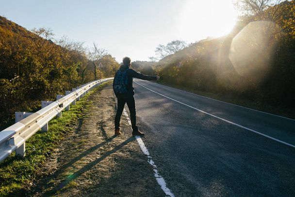 Человек, путешествующий автостопом по сельской дороге
 - Фото, изображение