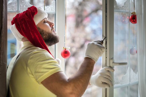 Man in Santa's Hat repairing window  - 写真・画像