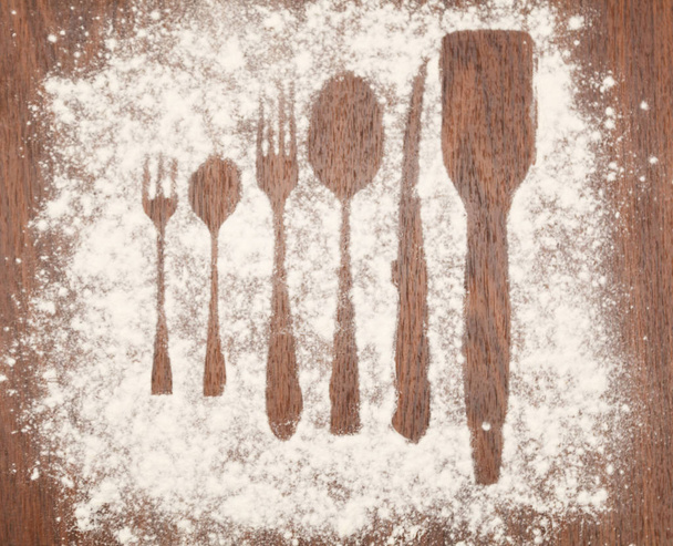 Spoons and forks and knife, flour sprinkled the wooden plank. - Fotografie, Obrázek