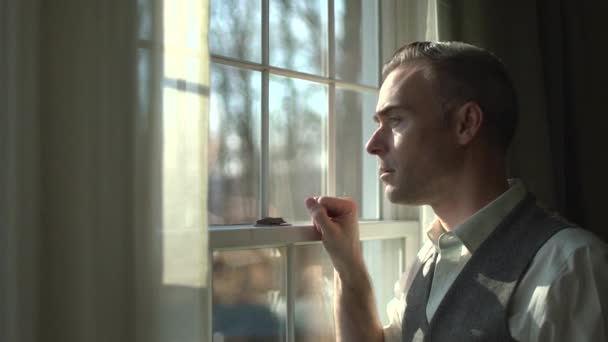 egy komoly kinézetű férfi kinéz az ablakon - Felvétel, videó