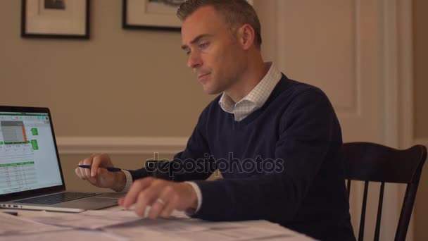 een man gaat over zijn rekeningen op zijn eetkamer tafel - Video