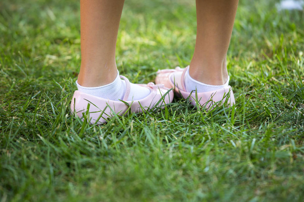 緑の草の中の子供のピンクの靴 - 写真・画像