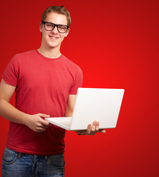 portrait d'un jeune étudiant tenant un ordinateur portable sur fond rouge
 - Photo, image