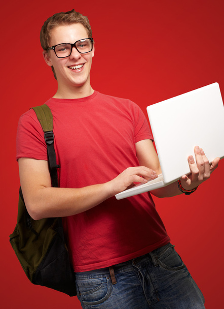 Porträt eines jungen Mannes mit Laptop und Rucksack über dem Kopf - Foto, Bild