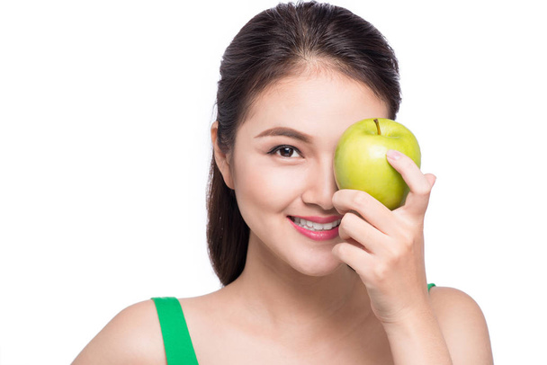 attraktive lächelnde junge asiatische Frau isst grünen Apfel isoliert - Foto, Bild