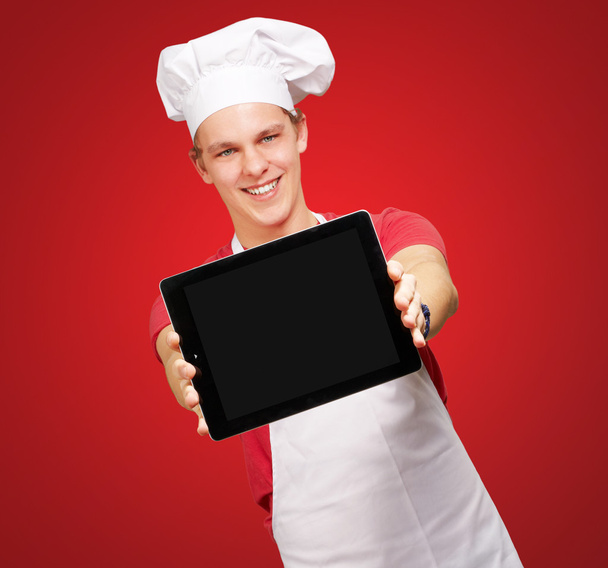 portrét mladého kuchaře člověka ukazuje digitální tabletu nad červeným bac - Fotografie, Obrázek