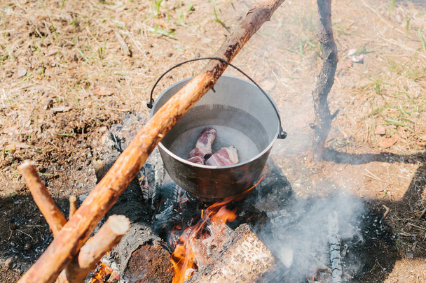  El fuego cerca del campamento. Cocinar comida en un incendio. Viaje al concepto salvaje
. - Foto, Imagen