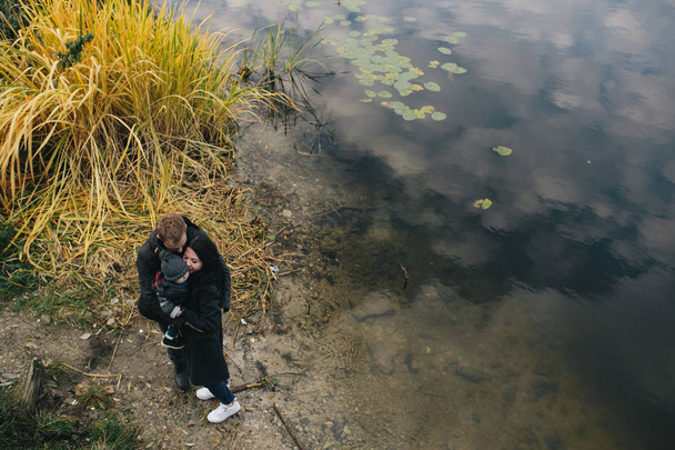 młode rodziny i syn spacerem wzdłuż brzegu jeziora - Zdjęcie, obraz