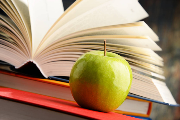 Composição com livros de capa dura e maçã
 - Foto, Imagem