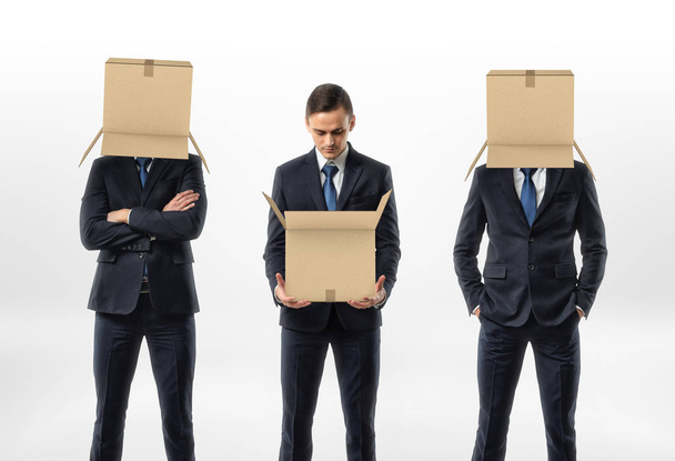 Businessman holding an open cardboard box, the other two are wearing the boxes on their heads. - Foto, immagini