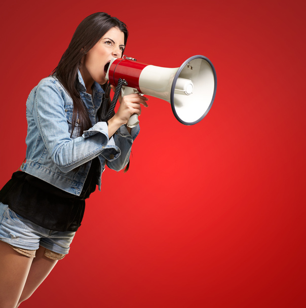 Portret van een jonge vrouw schreeuwen met megafoon tegen een rode b - Foto, afbeelding