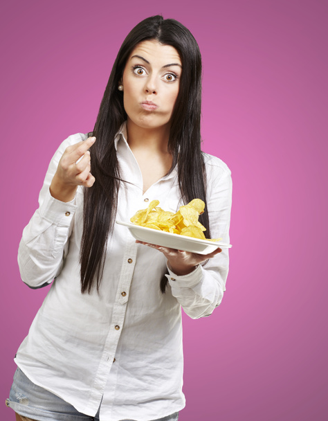 jovem mulher comer batatas fritas contra um fundo rosa
 - Foto, Imagem