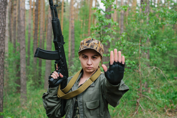 Женщина-солдат с оружием показывает, что рука остановилась
. - Фото, изображение
