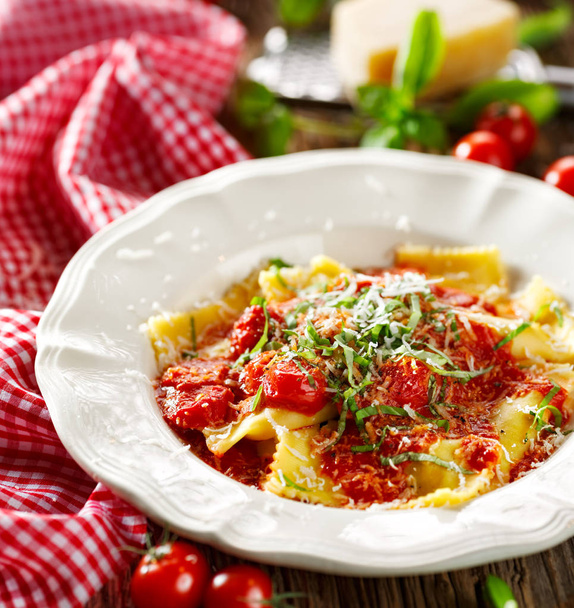 Ravioli rematado con salsa de tomate, queso de grana padano y albahaca fresca
  - Foto, imagen