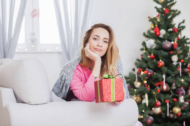 woman on the sofa holding a Christmas present - Foto, Imagen