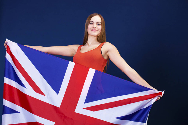 Happy young woman holding a flag of of Great Britain (British fl - Фото, зображення