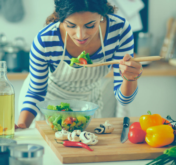 Fiatal nő eszik friss salátát a modern konyhában - Fotó, kép