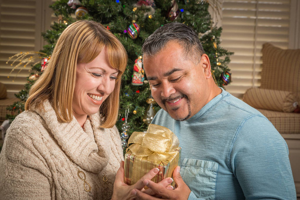 Young Mixed Race Couple with Present Near Christmas Tree - Фото, изображение