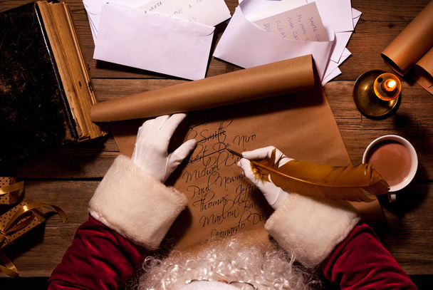 Santa Claus sitting at the table in his room and writing Christmas letter or wish list - Photo, image