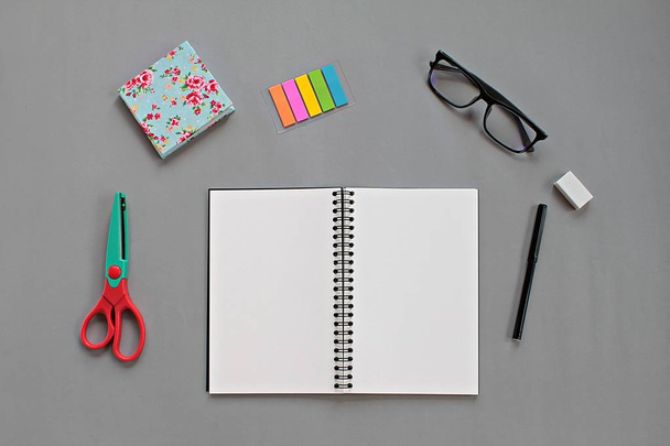 Top view of workspace desk with blank notebook and office stationery set on gray background - Foto, imagen