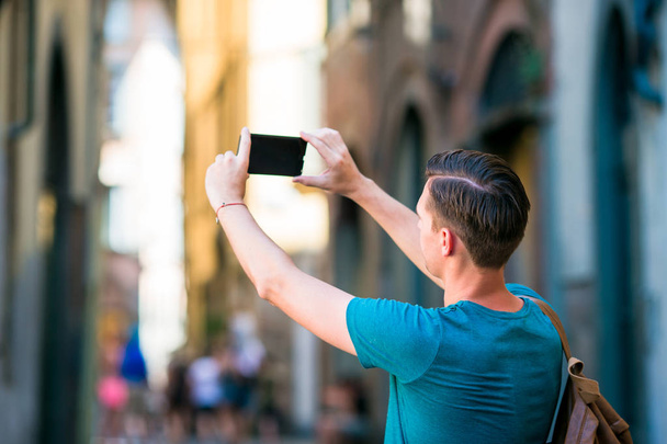 Touriste caucasien avec smartphone dans les mains marchant le long des rues étroites italiennes à Rome. Jeune garçon urbain en vacances explorer la ville européenne
 - Photo, image