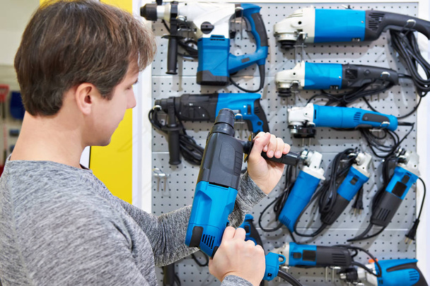 Man shopping for hammer drill in hardware store - 写真・画像