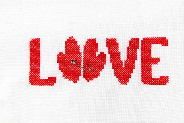 The word love embroidered red thread on white fabric. - Φωτογραφία, εικόνα