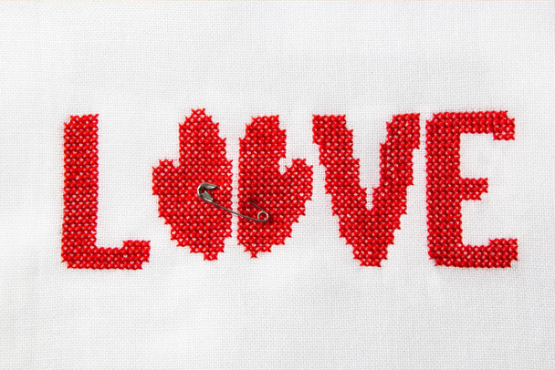 Het woord liefde rode draad op witte stof geborduurd. - Foto, afbeelding