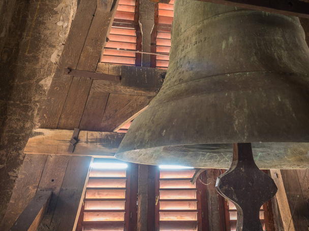 Detalle de una antigua campana de iglesia en el campanario rojo de madera
. - Foto, Imagen