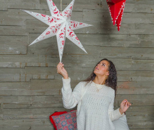 before Christmas beautiful girl in a white sweater playing with Christmas star. - Foto, imagen