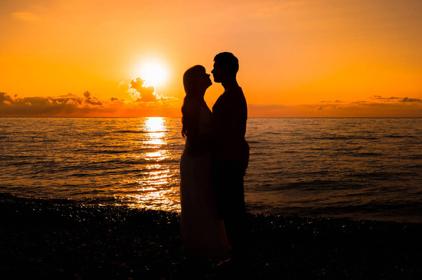 Двоє молодих коханців стоять на пляжі і дивляться один на одного
 - Фото, зображення