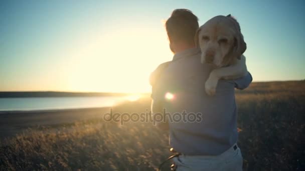 πίσω όψη του ο άνθρωπος που μεταφέρουν γέρικο σκυλί σε ήλιο φως αργή κίνηση - Πλάνα, βίντεο