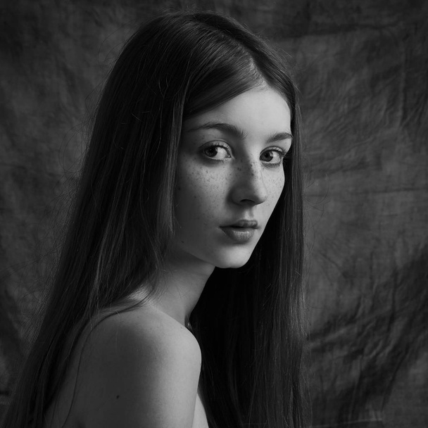 Dramatický černobílý portrét krásné osamělé dívky s pihami izolované na tmavém pozadí ve studiu záběr - Fotografie, Obrázek