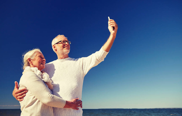 seniors con smartphone tomando selfie en la playa
 - Foto, imagen
